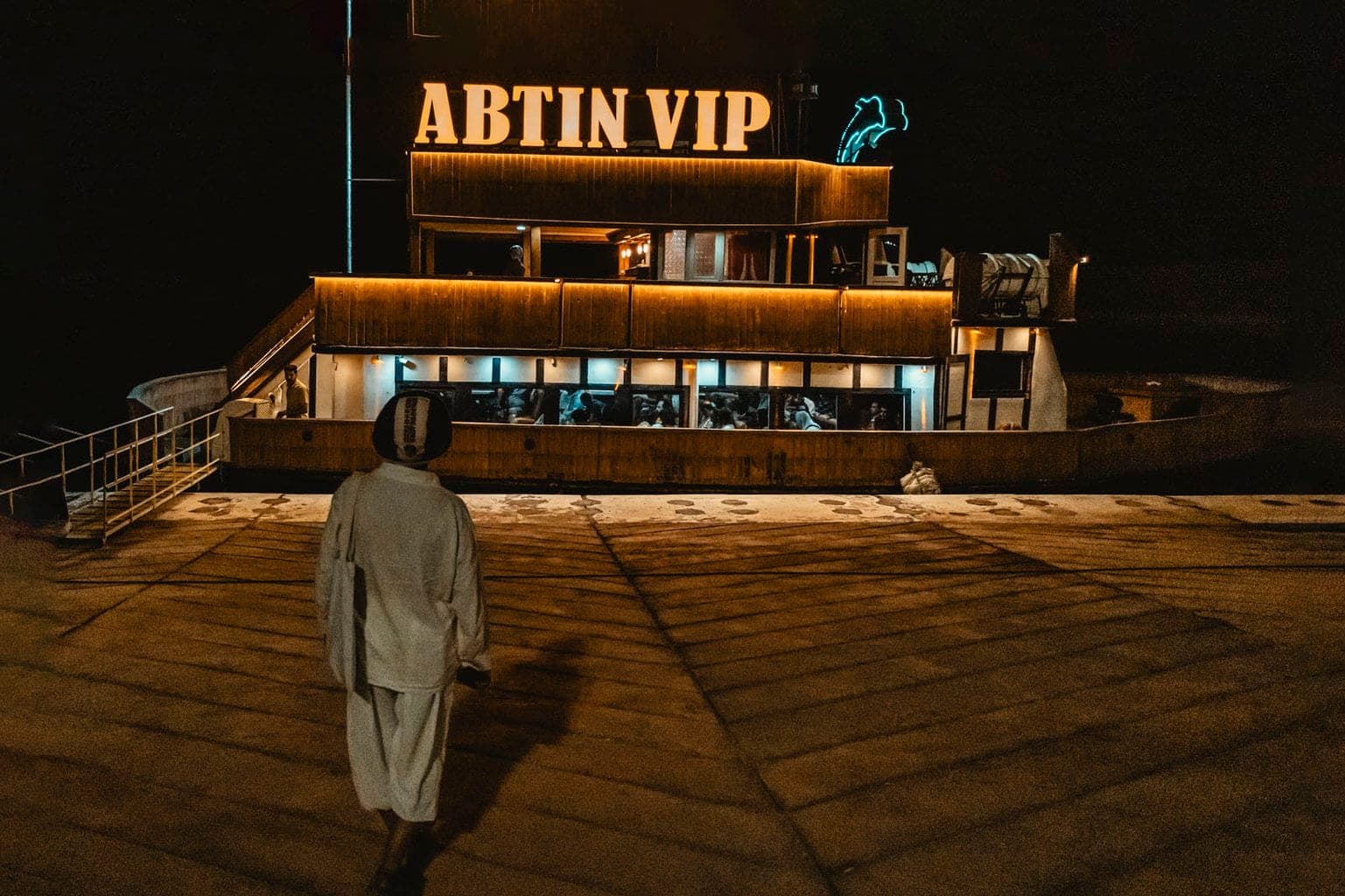 کشتی آبتین VIP پهلوگرفته در اسکلهٔ ابرکاوان قشم در شب با تابلوی نورانی و نئون دلفین
