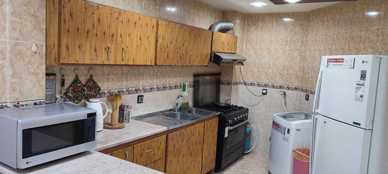 آشپزخانه با کابینت چوبی، اجاق گاز و سینک در آپارتمان سام و زال ۱ قشم