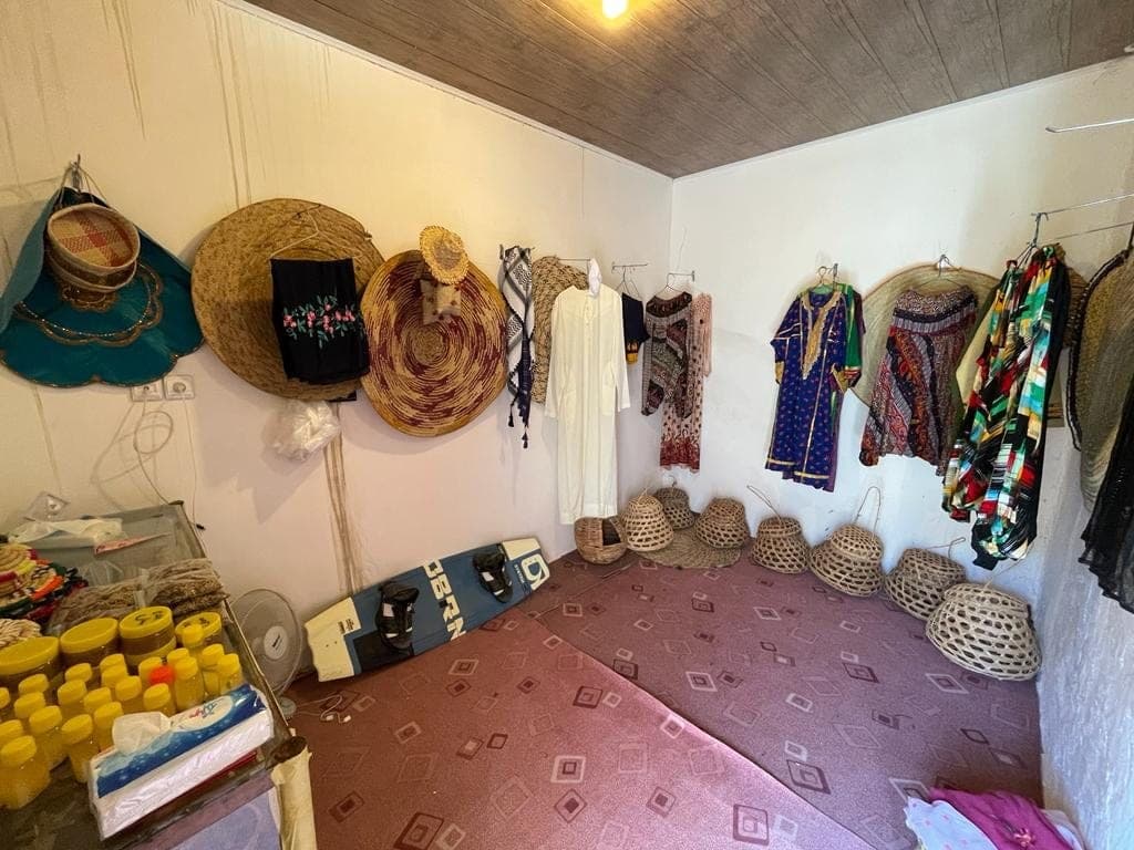 فضای سنتی با کلاه و پوشاک محلی آویزان و سبد میوه در بوم‌گردی پرویز امینی قشم