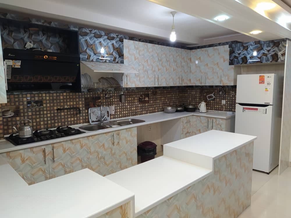 آشپزخانهٔ مجهز با کابینت سفید و کانتر در آپارتمان سام ۱ واحد ۷ قشم