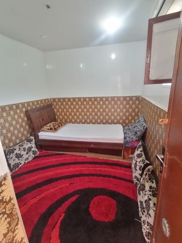 تخت یک‌نفره کنار درب چوبی و کابینت دیواری سوئیت طوفان درگهان قشم