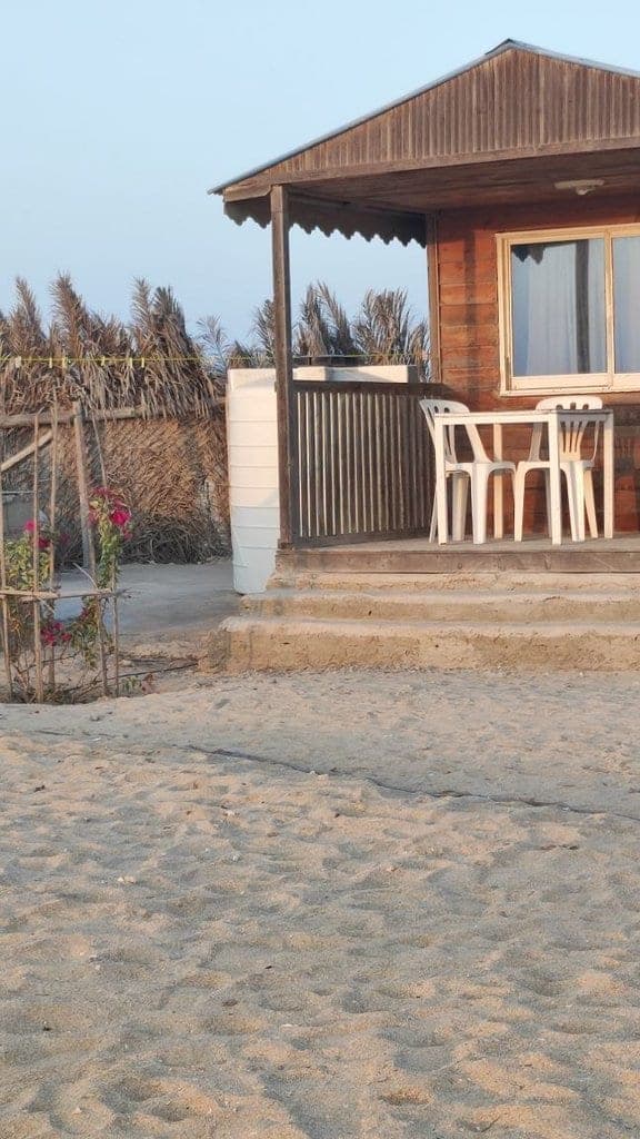 فضای نشیمن بیرونی با صندلی کنار کلبه در بوم‌گردی فین دلفین قشم