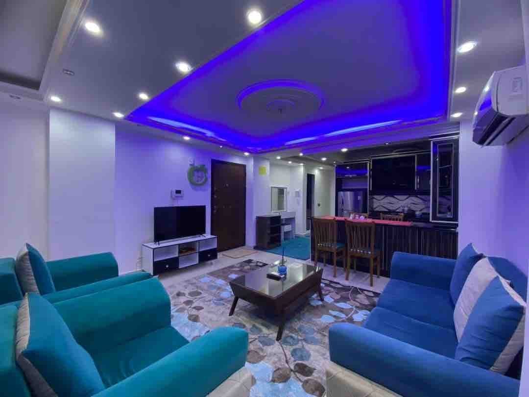 نشیمن دلباز با مبلمان فیروزه‌ای و دکوراسیون مدرن در آپارتمان لوکس سام پلاس ۱ قشم