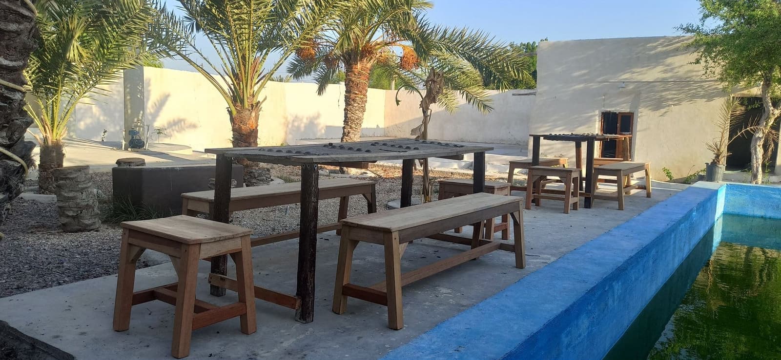 نشیمن سنتی سایه‌دار با ستون‌ها در کنار استخر بوم‌گردی میلس قشم