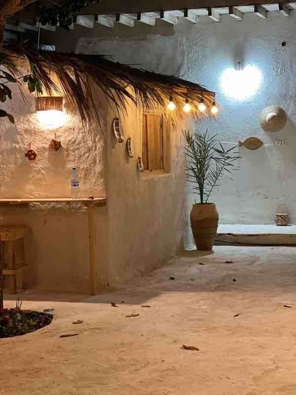 حیاط در شب با نورپردازی و دیوار کاهگلی در اقامتگاه سنتی خانه شیوا هرمز