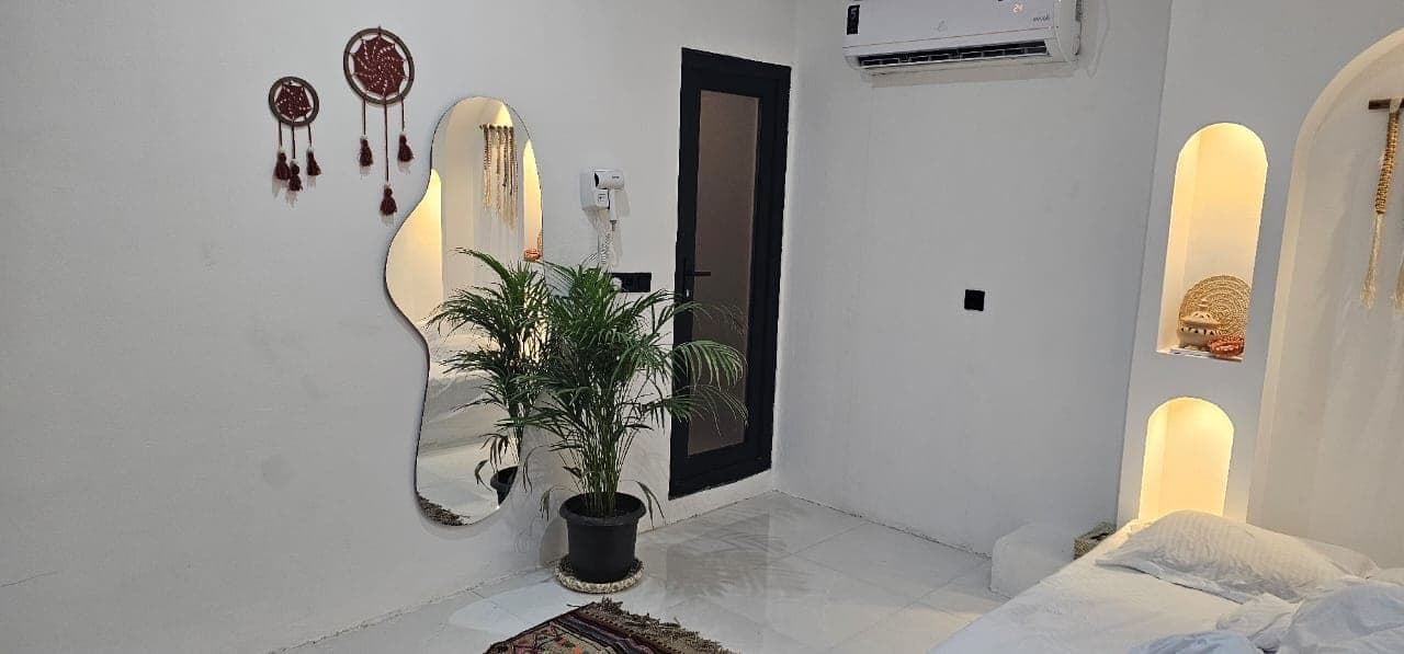 اتاق‌خواب با آینهٔ مدرن، آویز سنتی و گلدان در ویلا عمارت رستم قشم