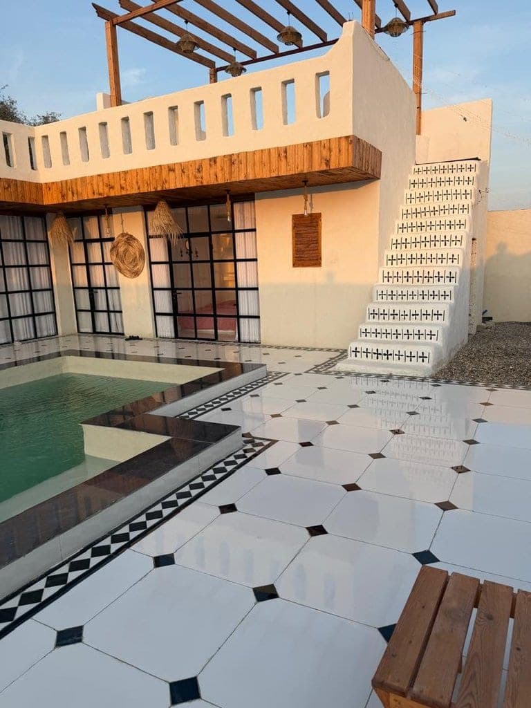 نمای روز حیاط با استخر روباز، پله کاشی‌کاری و کف سنگ‌فرش شطرنجی در ویلا عمارت رستم قشم
