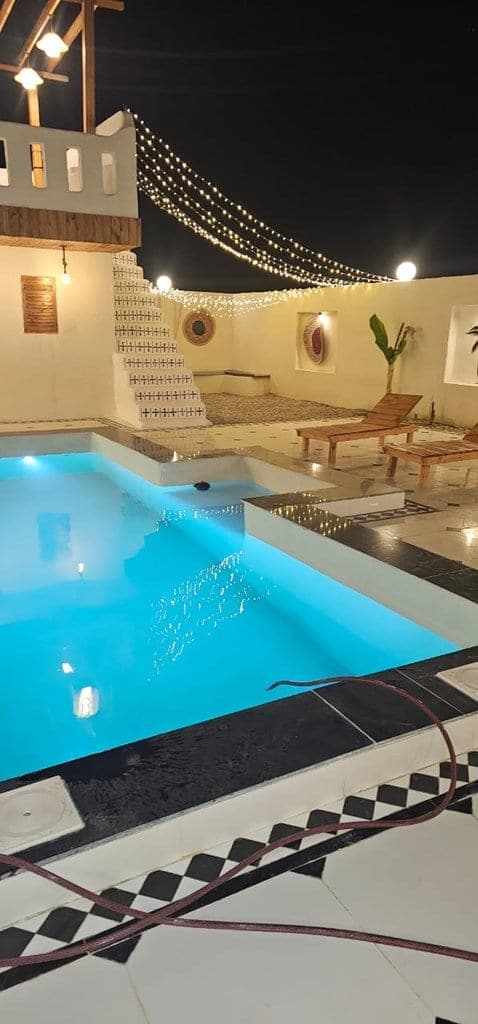 استخر روباز با پلهٔ کاشی‌کاری و آلاچیق در شب در حیاط ویلا عمارت رستم قشم