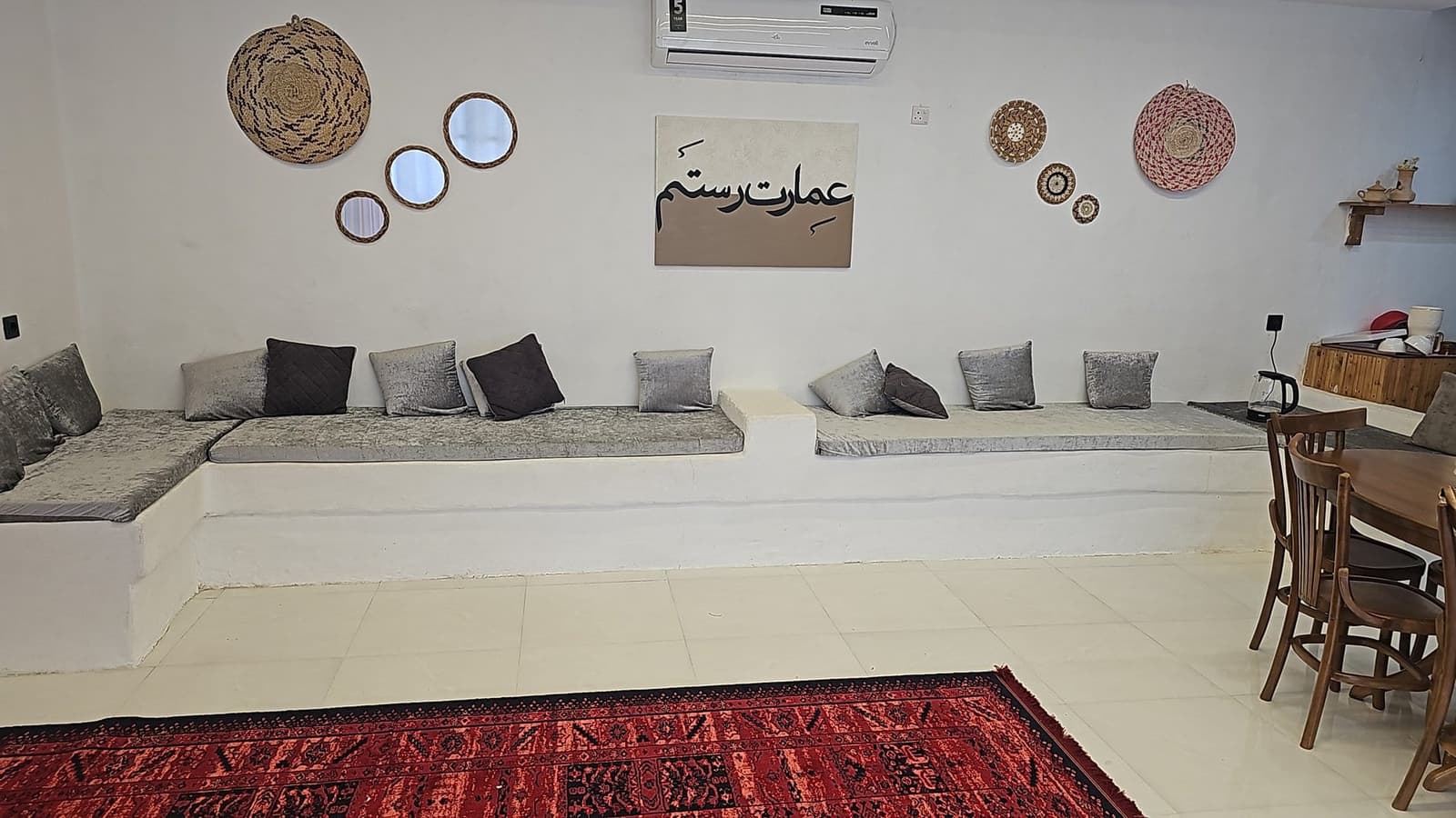 نشیمن سنتی با تابلوی «عمارت رستم» و نشیمن‌گاه‌های دیواری در ویلا عمارت رستم قشم