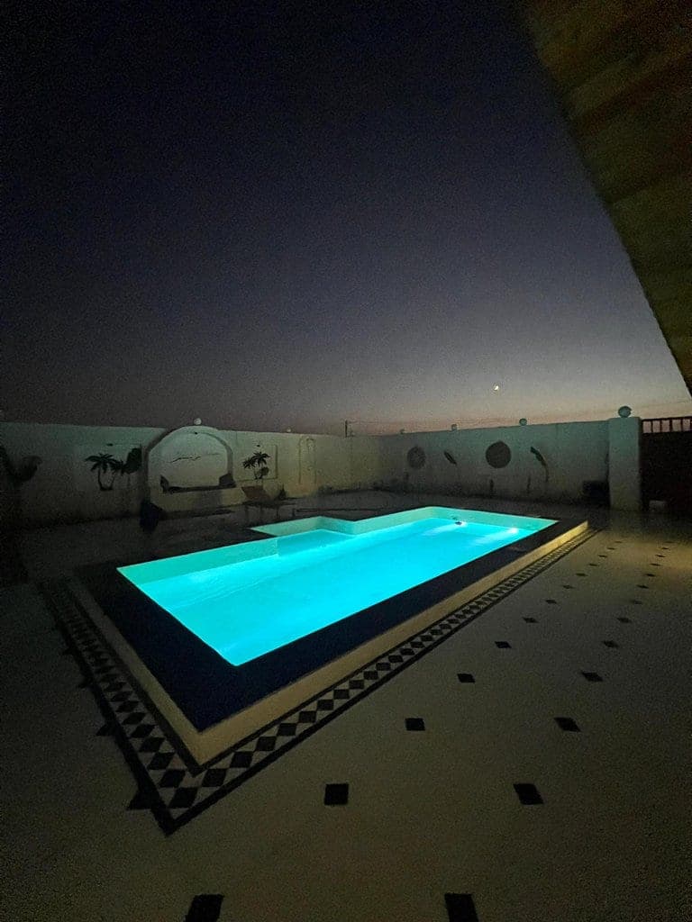 استخر روباز با نور آبی در شب در حیاط ویلا استخردار عمارت رستم قشم