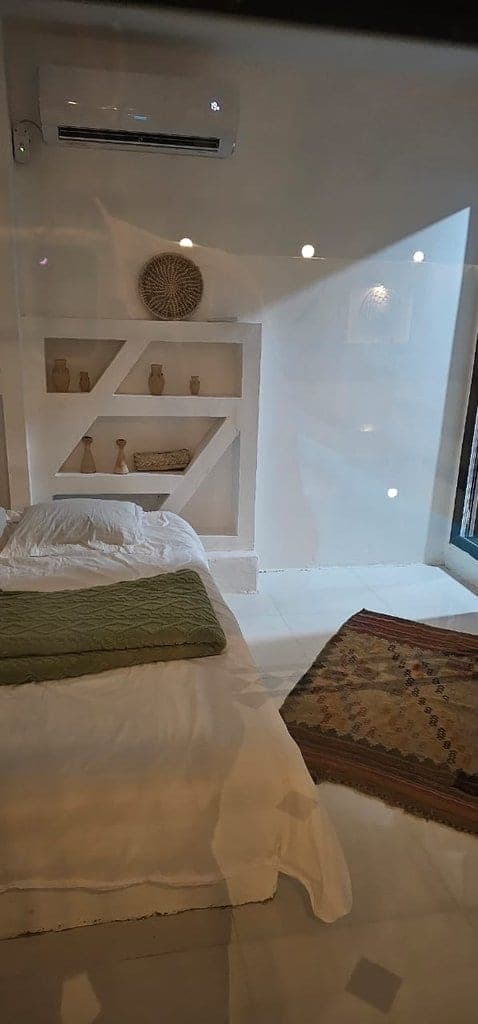 اتاق‌خواب روشن با تخت دونفره و طاقچهٔ کنج در ویلا عمارت رستم قشم