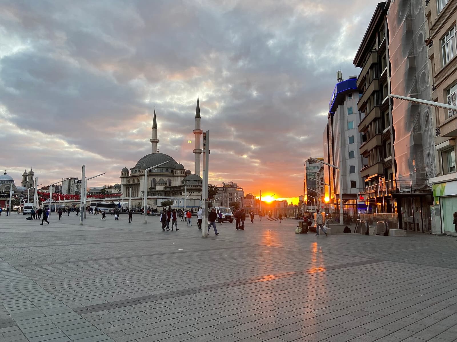 میدان تکسیم استانبول هنگام غروب با مسجد تکسیم و عبور پیادهها در محوطه سنگفرش